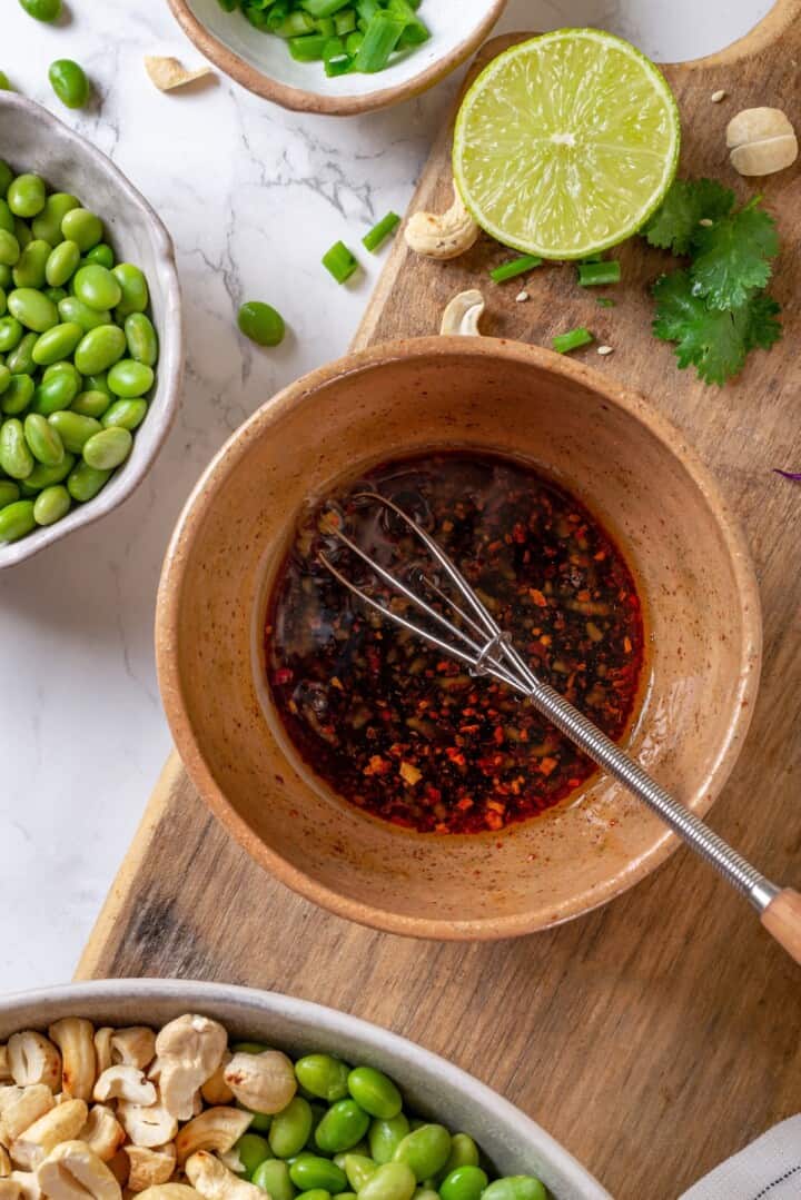 Whisking ginger garlic dressing in bowl.