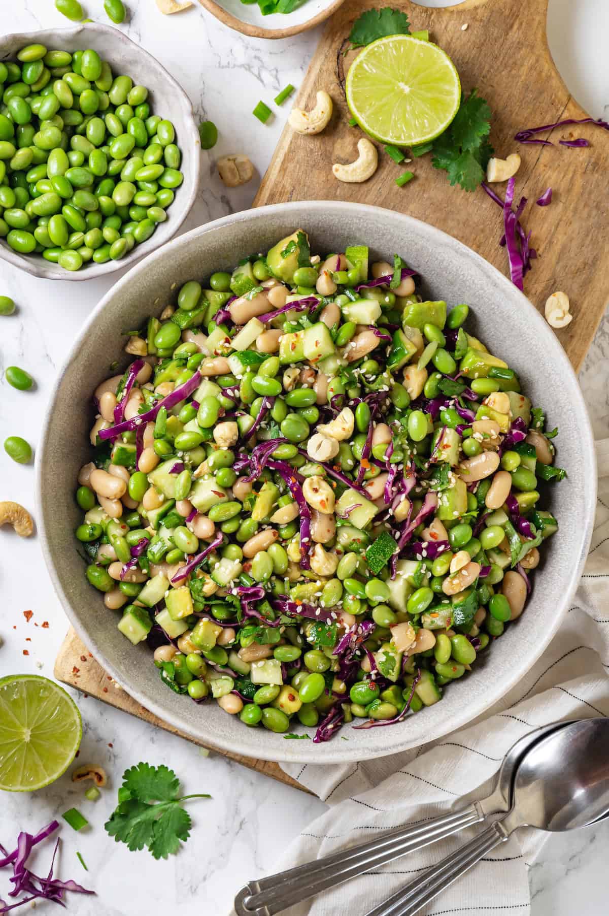 Edamame salad in bowl set on wooden board.
