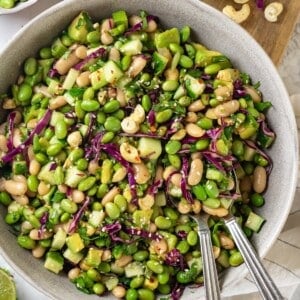 Edamame salad in bowl with two spoons.