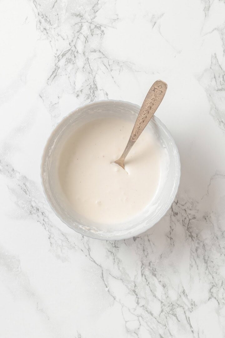 Coconut cream mixed with cornstarch in bowl with spoon.