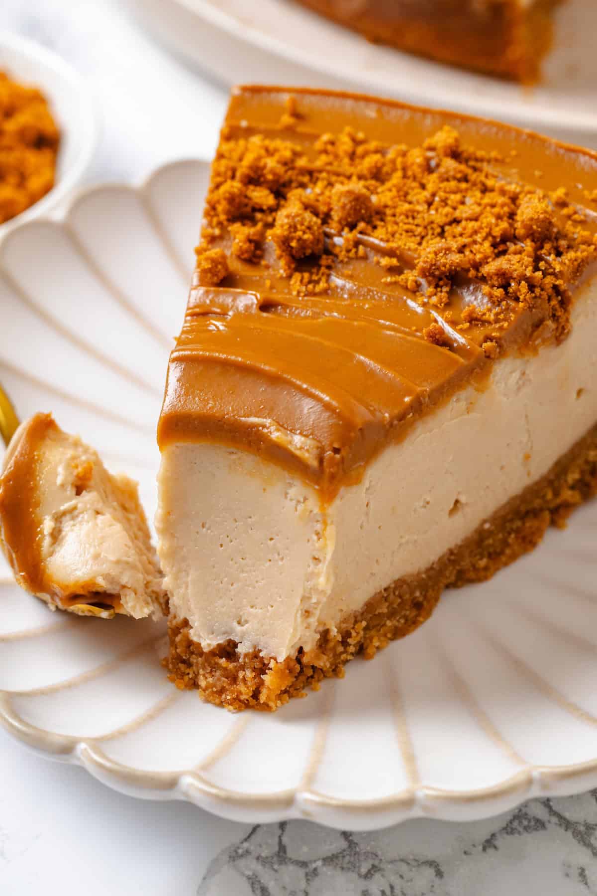 Slice of Biscoff cheesecake on plate with tip on fork.