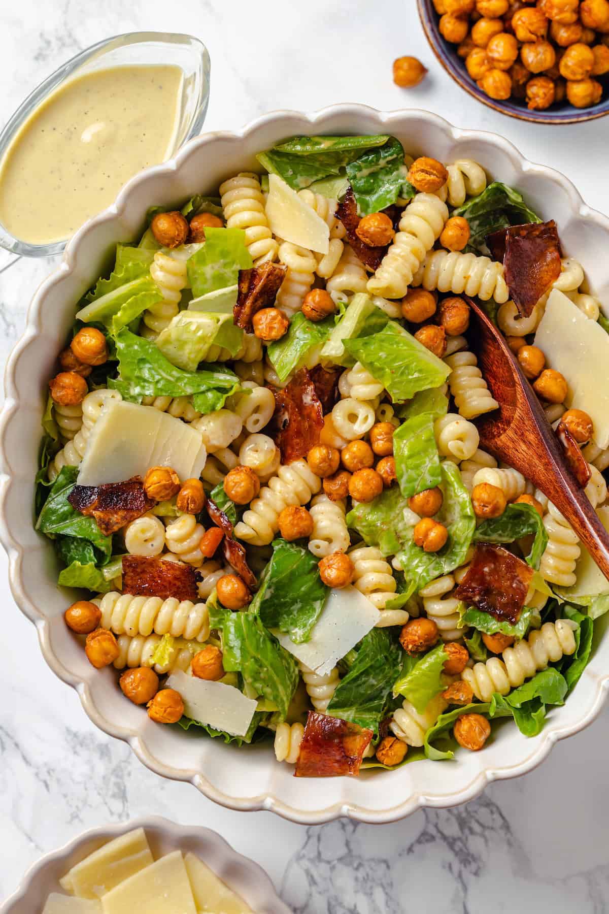 Bowl of caesar pasta salad with wooden spoon.
