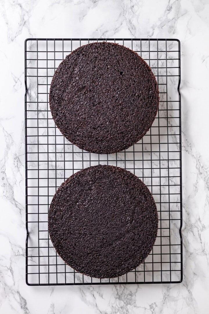 Two chocolate cake layers on wire rack.