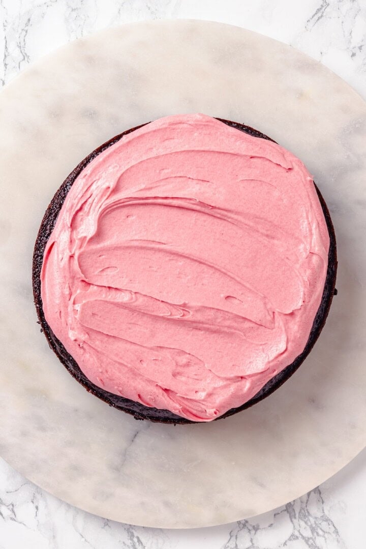 Pink frosting added to chocolate cake.