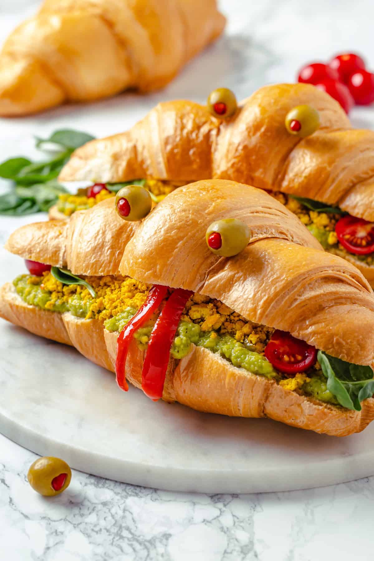 Two vegan monster breakfast sandwiches on marble board