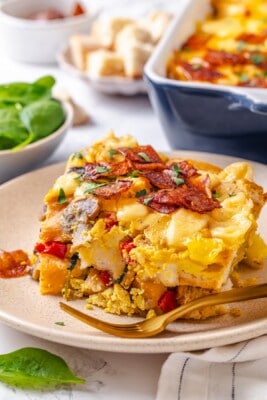 Slice of vegan overnight breakfast strata on plate with fork