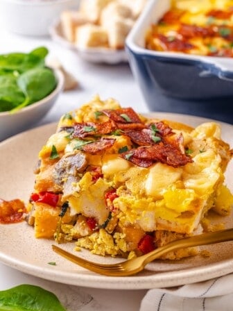 Slice of vegan overnight breakfast strata on plate with fork