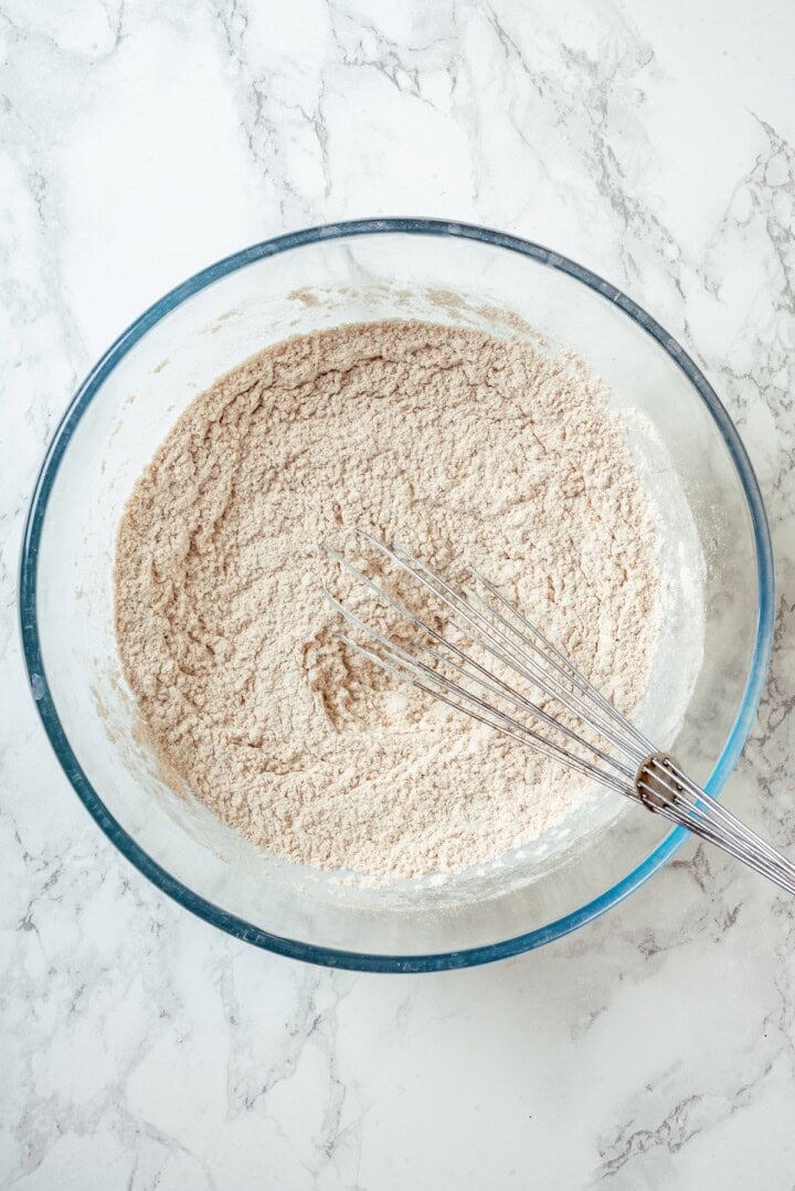 Dry ingredients in glass bowl with whisk.