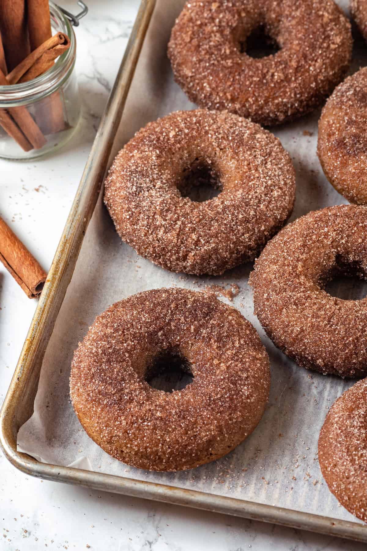 Vegan baked apple cider donuts on parchment-lined pan.