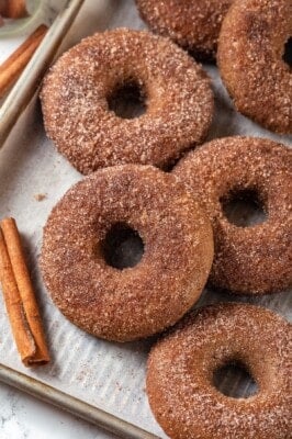 Baked apple cider donuts on parchment-lined sheet pan.