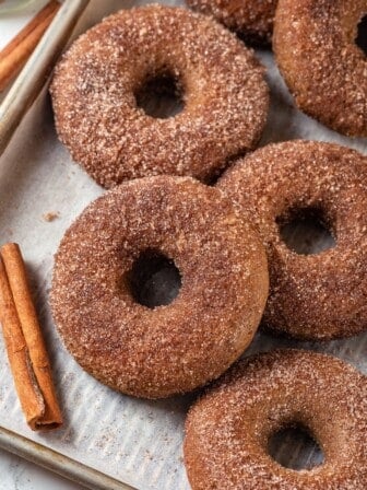 Baked apple cider donuts on parchment-lined sheet pan.