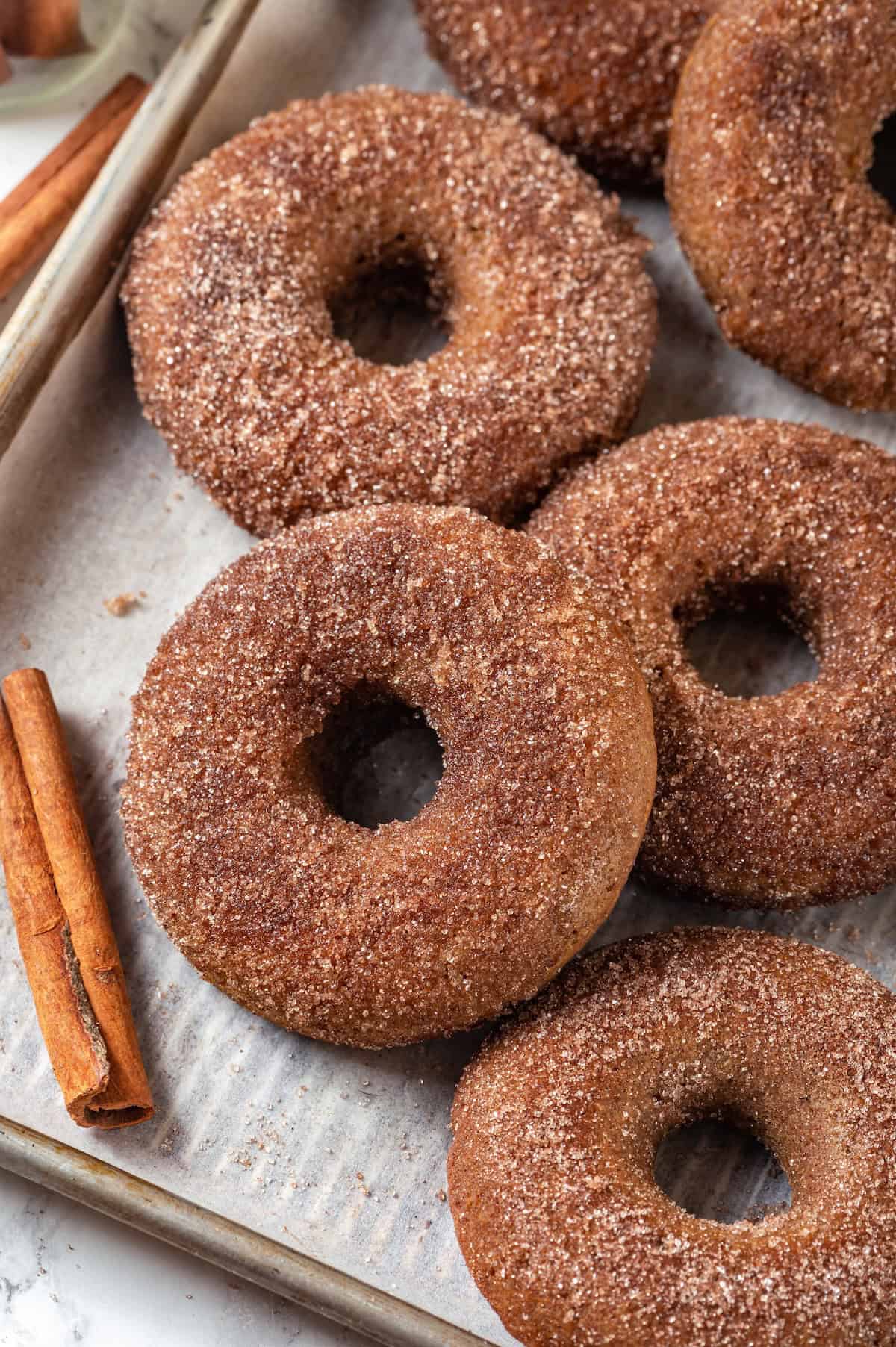 Baked apple cider donuts on parchment-lined sheet pan.