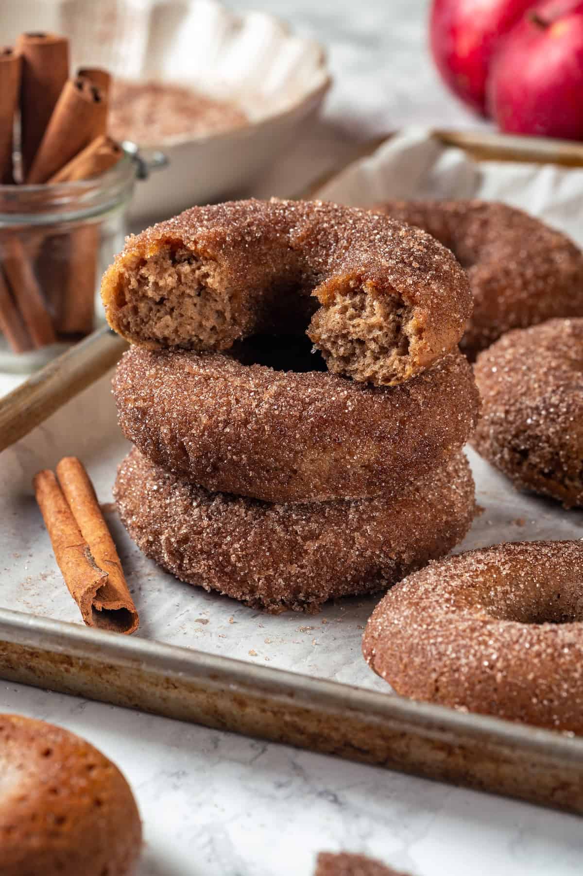 Stack of 3 apple cider donuts with top donut broken in half to show tender crumb.