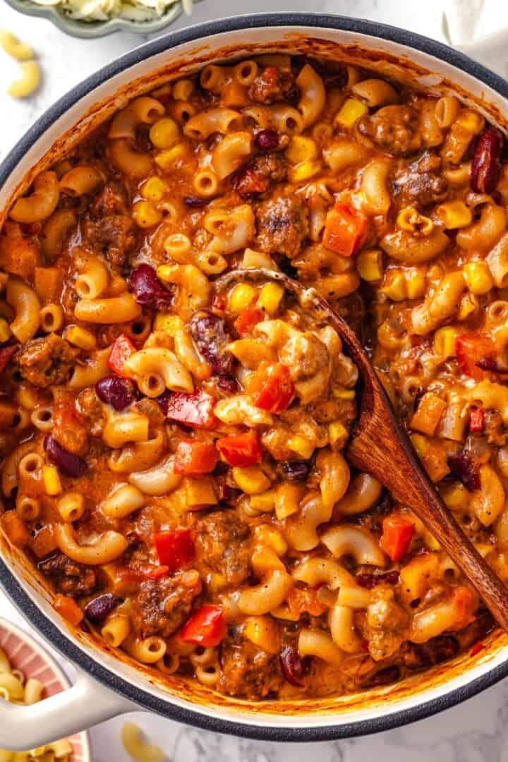 Pot of chili mac and cheese with wooden spoon.