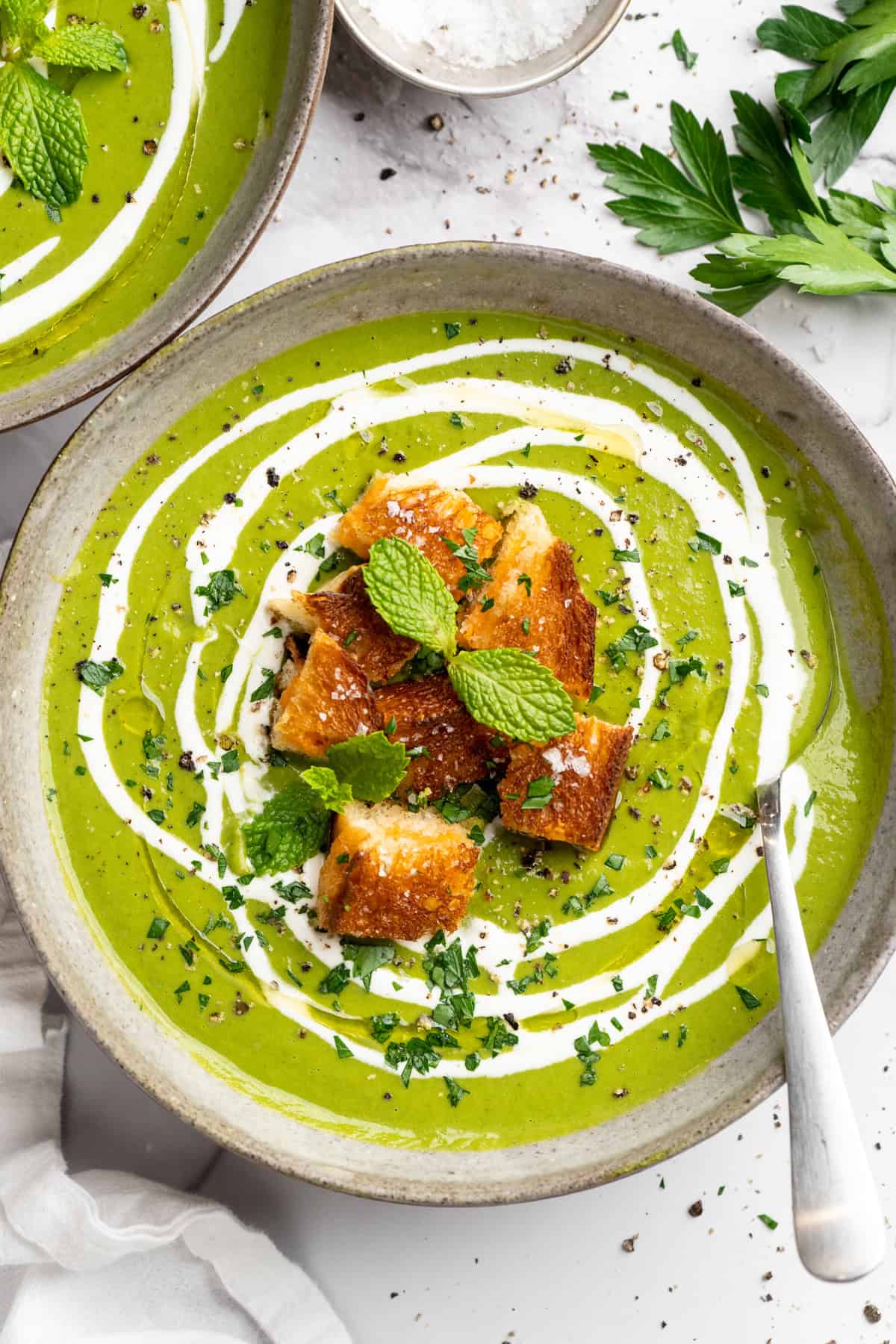 Eliminate waste and make a delicious dinner with this Broccoli Fridge Clean-Out Soup! Rich and creamy, with optional grilled cheese croutons. Bowl of broccoli fridge clean-out soup with grilled cheese croutons and swirl of coconut cream.