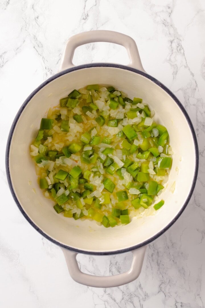 This Stuffed Pepper Soup is a satisfying vegan meal, with walnut “meat,” green peppers, rice and veggies in a rich tomato broth. Delicious! Onions and green peppers softening in Dutch oven.