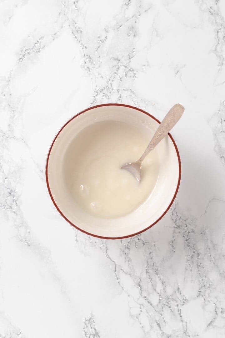 Bowl of vanilla glaze with spoon.