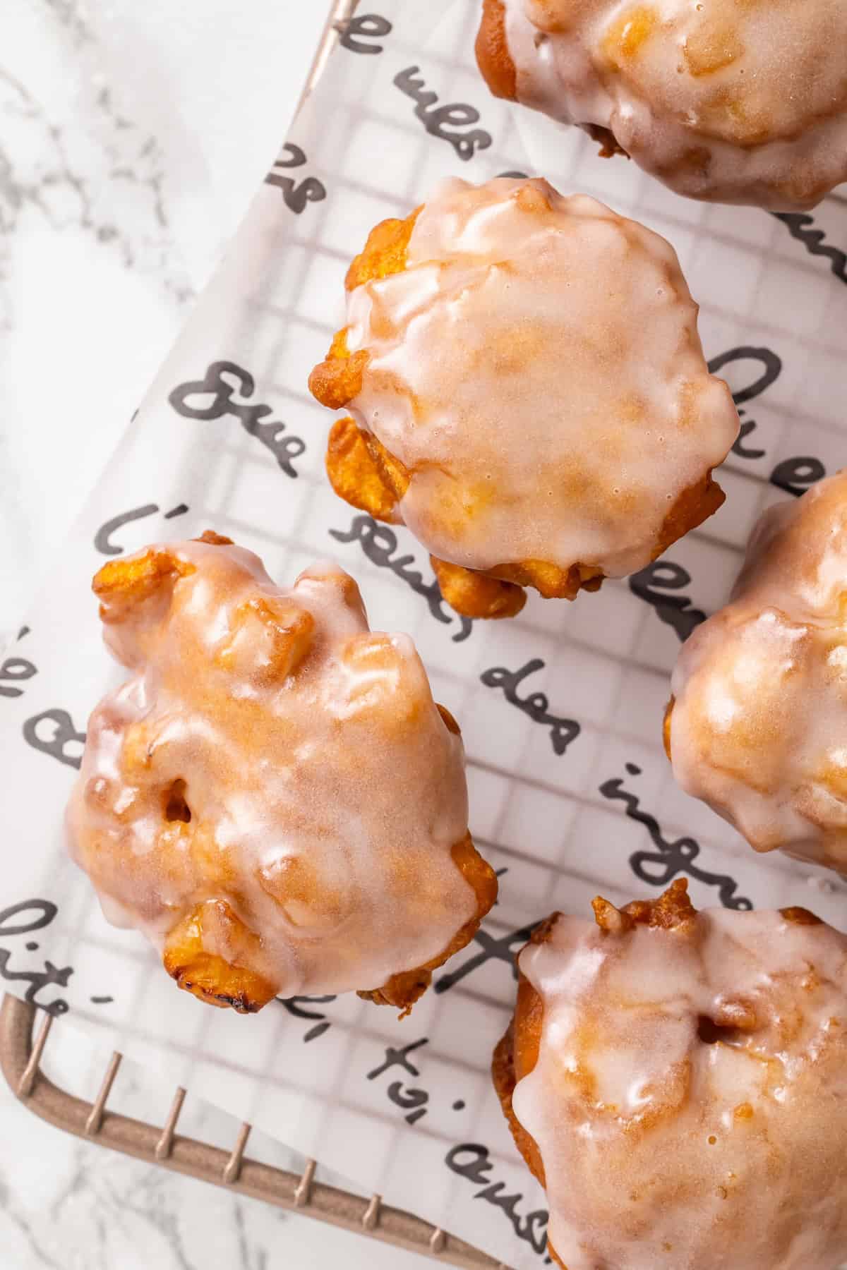 Glazed apple fritters on cooling rack.