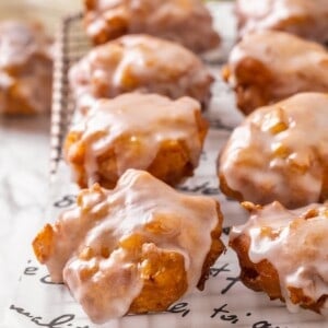 Vegan apple fritters on parchment-lined wire rack.
