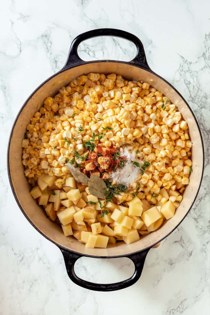 With sweet corn, tender potatoes and a creamy broth, this vegan Corn Chowder recipe is every bit as delicious as the traditional version! Corn, seasonings, and potatoes added to Dutch oven.