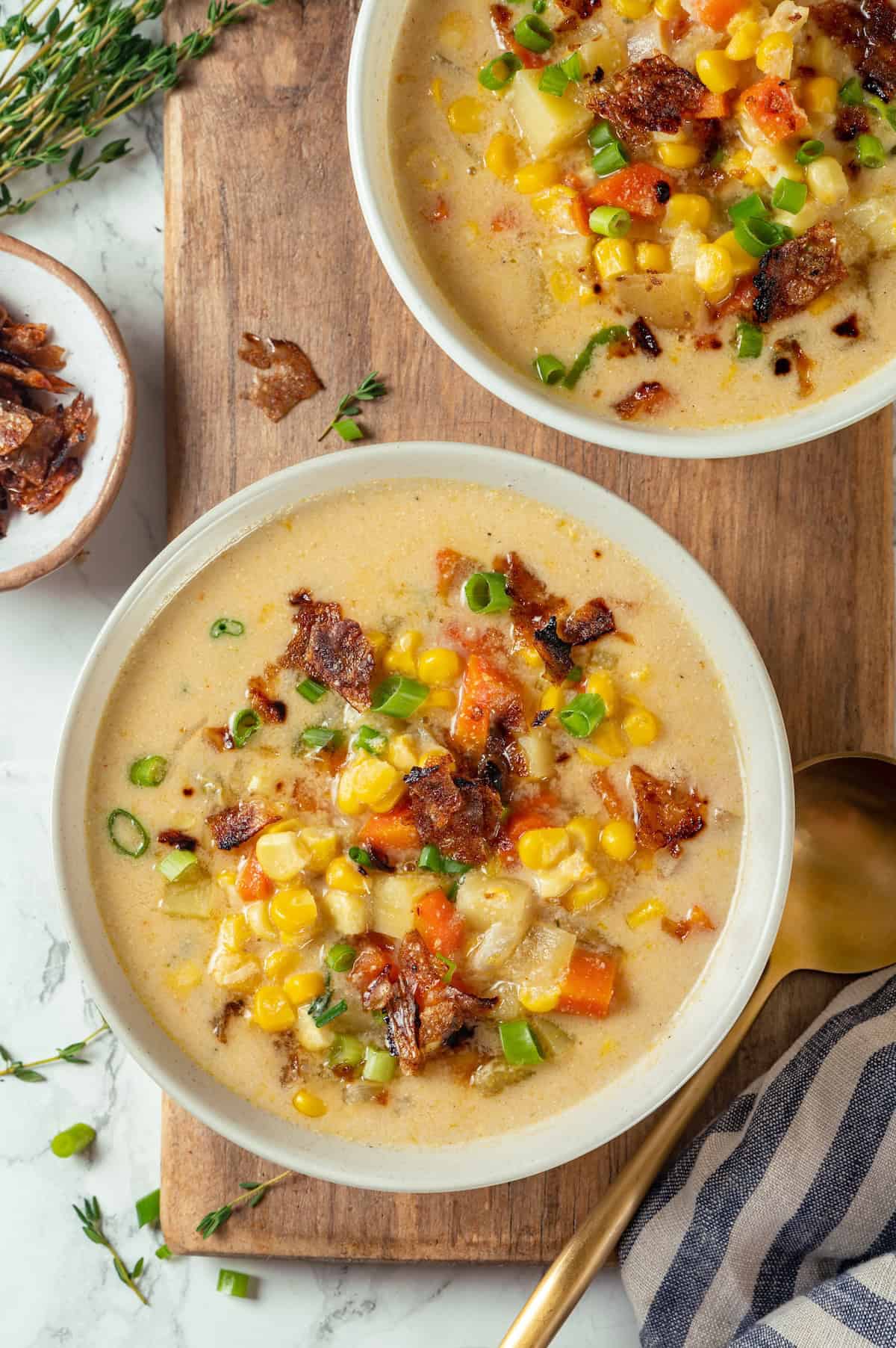 With sweet corn, tender potatoes and a creamy broth, this vegan Corn Chowder recipe is every bit as delicious as the traditional version! Two bowls of creamy corn chowder with vegan bacon.