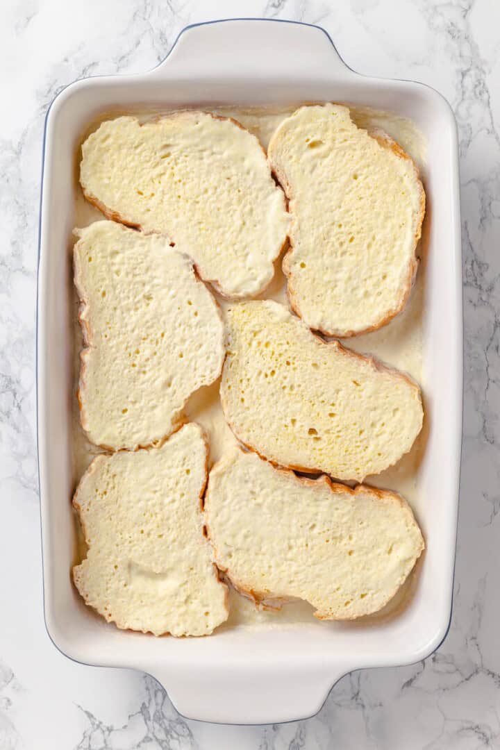 With a rich vegan custard and caramel, this Creme Brûlée French Toast has the flavour of the classic dessert in crowd-pleasing breakfast form! Bread soaking in custard in baking dish.