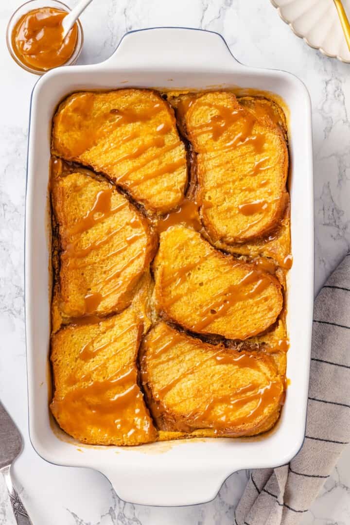 With a rich vegan custard and caramel, this Creme Brûlée French Toast has the flavour of the classic dessert in crowd-pleasing breakfast form! Vegan creme brulee French toast in casserole dish with caramel drizzle.