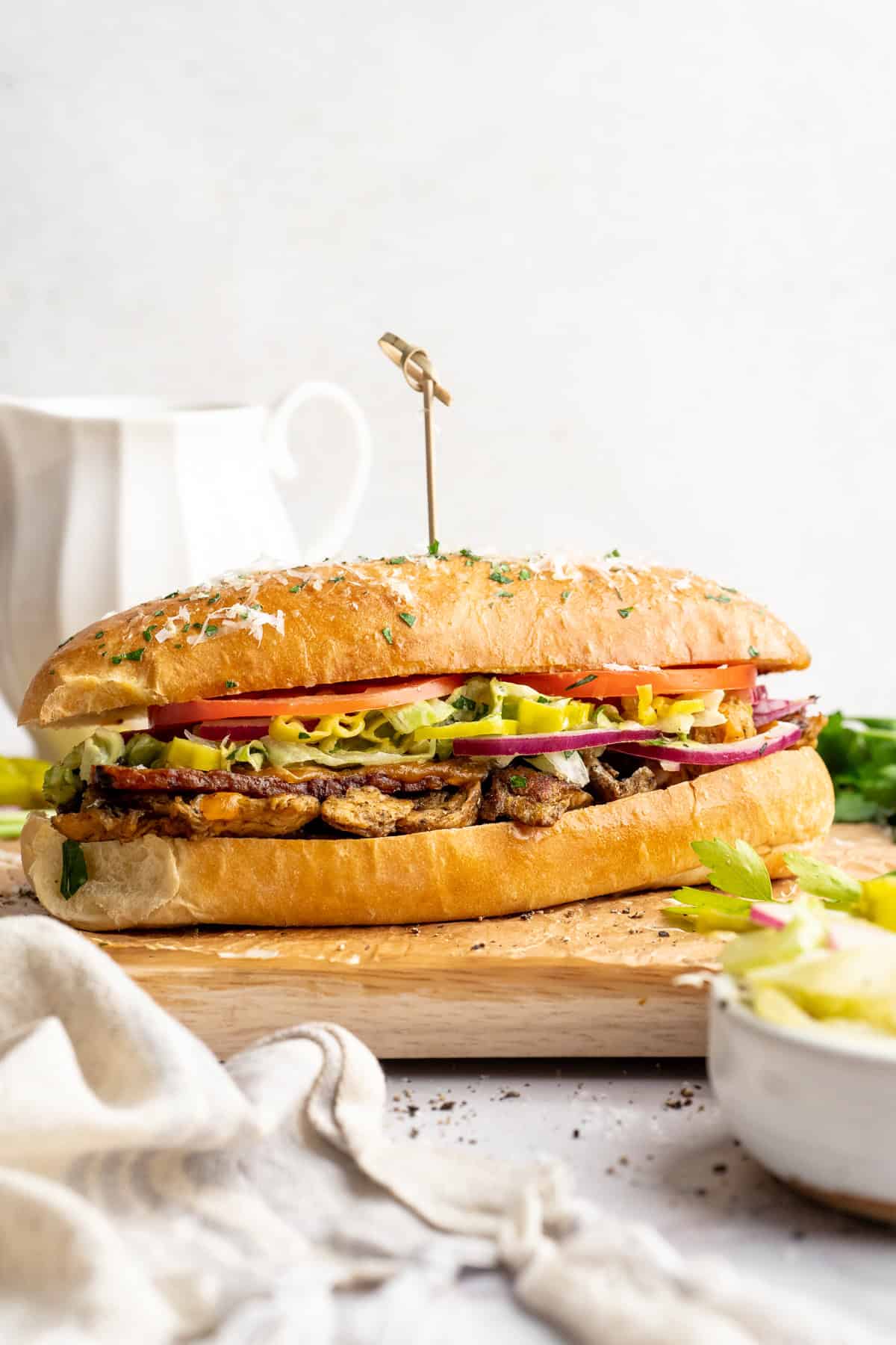 Vegan grinder sandwich on wooden cutting board.