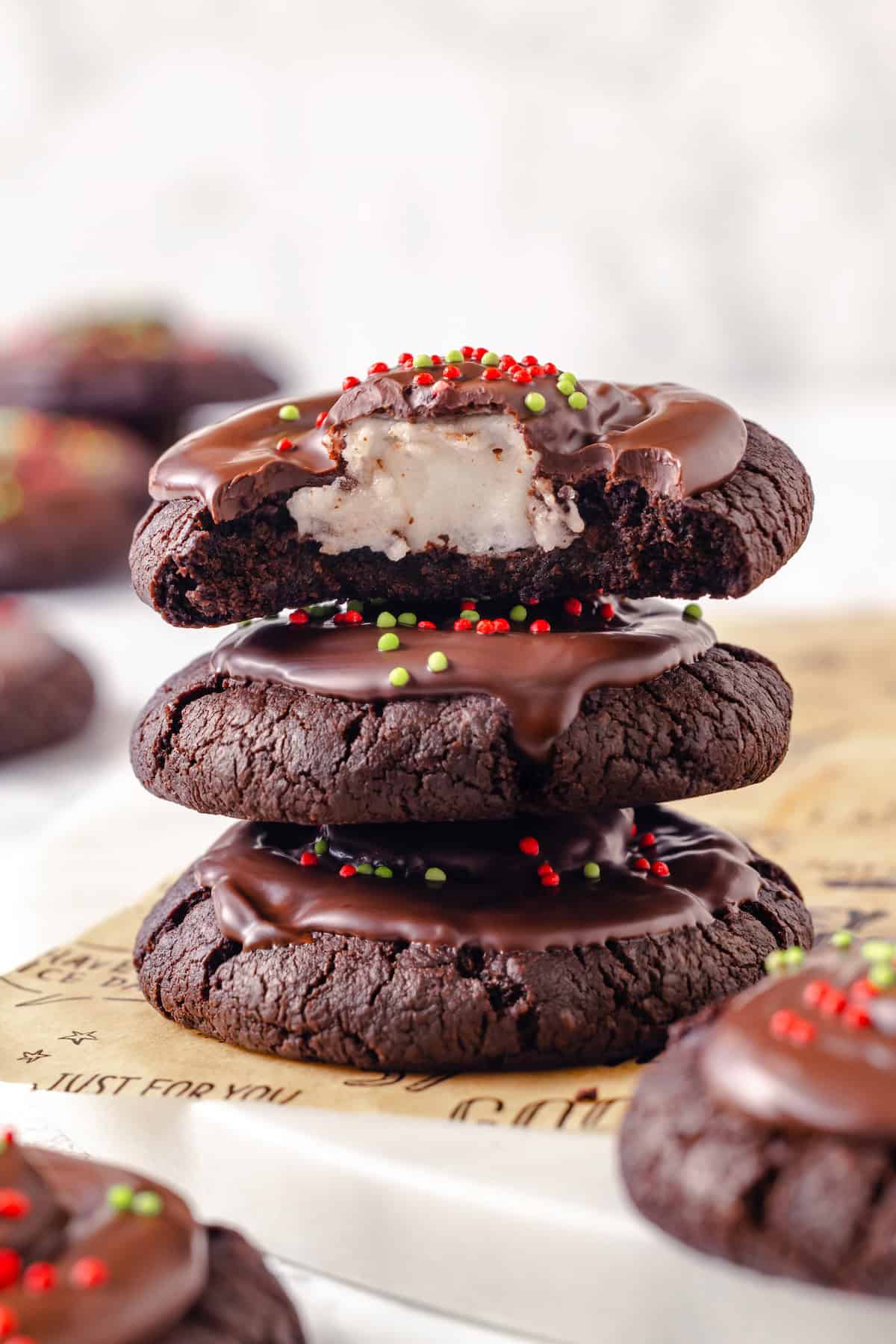 Stack of 3 hot chocolate cookies with top cookie bitten into to show marshmallow.