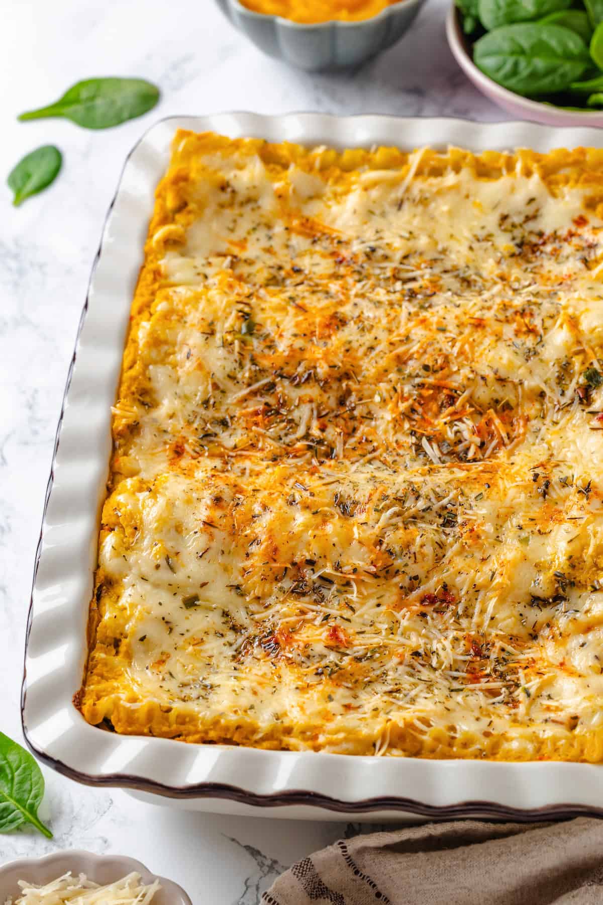 With layers of creamy squash, spinach ricotta and vegan cheese, this butternut squash lasagna is hearty, rich and full of cozy fall flavour! Butternut squash lasagna in baking dish.