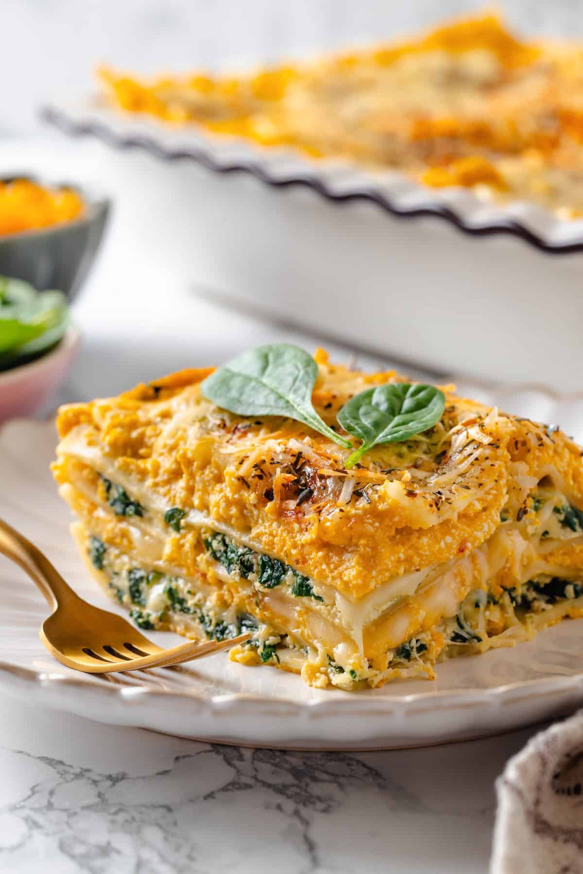 With layers of creamy squash, spinach ricotta and vegan cheese, this butternut squash lasagna is hearty, rich and full of cozy fall flavour! Slice of butternut squash lasagna on plate with fork.