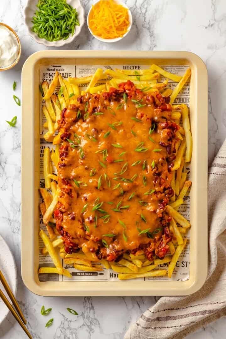 Vegan chili cheese fries on parchment lined baking sheet.