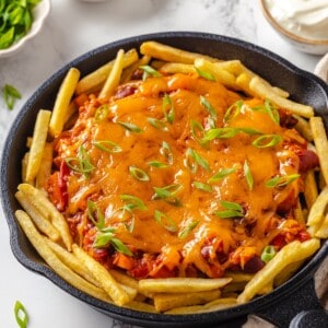 Skillet of chili cheese fries with scallions.