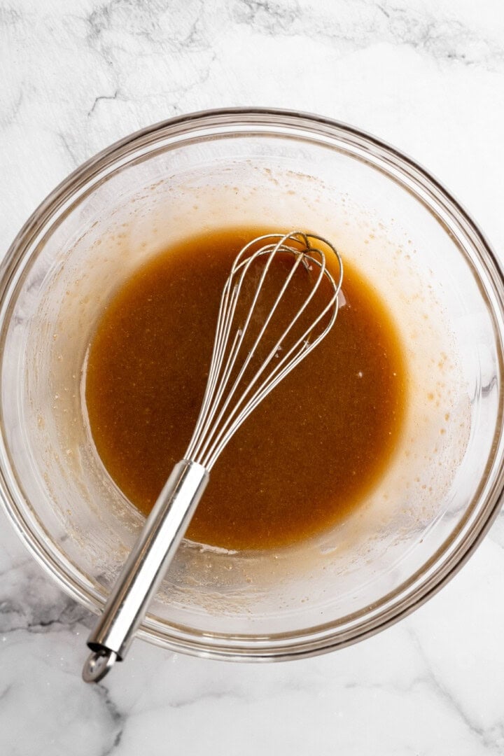 Wet ingredients mixed in glass bowl with whisk.
