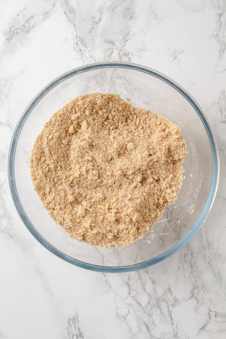 This vegan coffee cake recipe is a bakery-style treat! Moist and tender, with a cinnamon swirl and irresistible crumb topping. Delicious! Crumb mixture in glass mixing bowl.