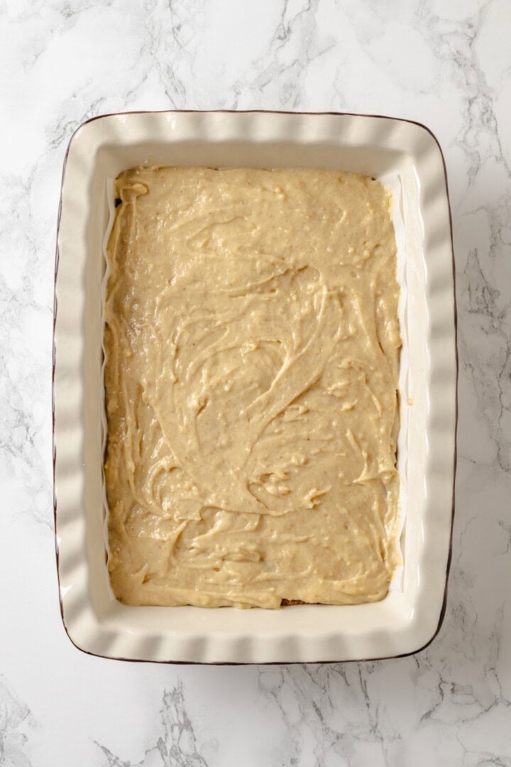 This vegan coffee cake recipe is a bakery-style treat! Moist and tender, with a cinnamon swirl and irresistible crumb topping. Delicious! Coffee cake batter in baking dish.