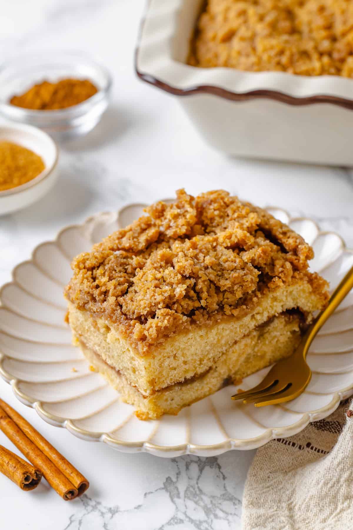 This vegan coffee cake recipe is a bakery-style treat! Moist and tender, with a cinnamon swirl and irresistible crumb topping. Delicious! Slice of vegan coffee cake on plate with fork.
