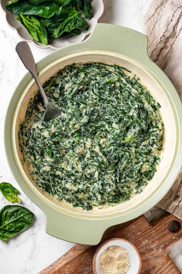 Spoon in skillet of creamed spinach.