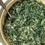 Skillet of vegan creamed spinach with spoon inside.