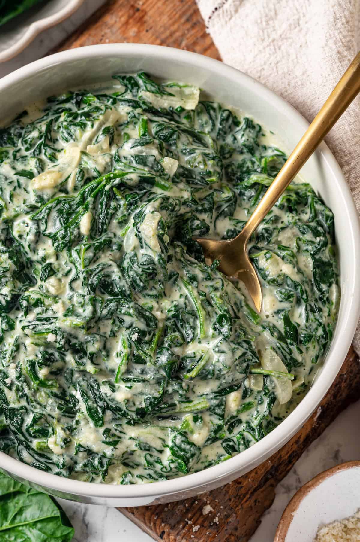 Bowl of creamed spinach with spoon.