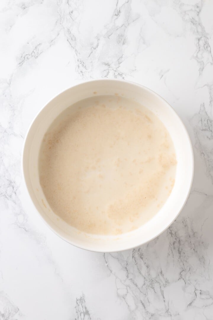 Soft, gooey and sticky, this Vegan Monkey Bread recipe is an irresistible pull-apart treat that's perfect for weekend brunches and holidays! Wet ingredients for monkey bread dough in bowl.