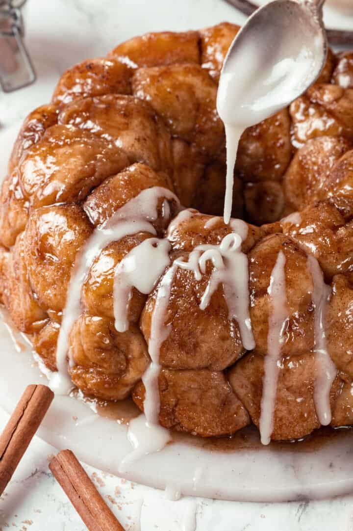 Soft, gooey and sticky, this Vegan Monkey Bread recipe is an irresistible pull-apart treat that's perfect for weekend brunches and holidays! Spoon drizzling glaze onto monkey bread.