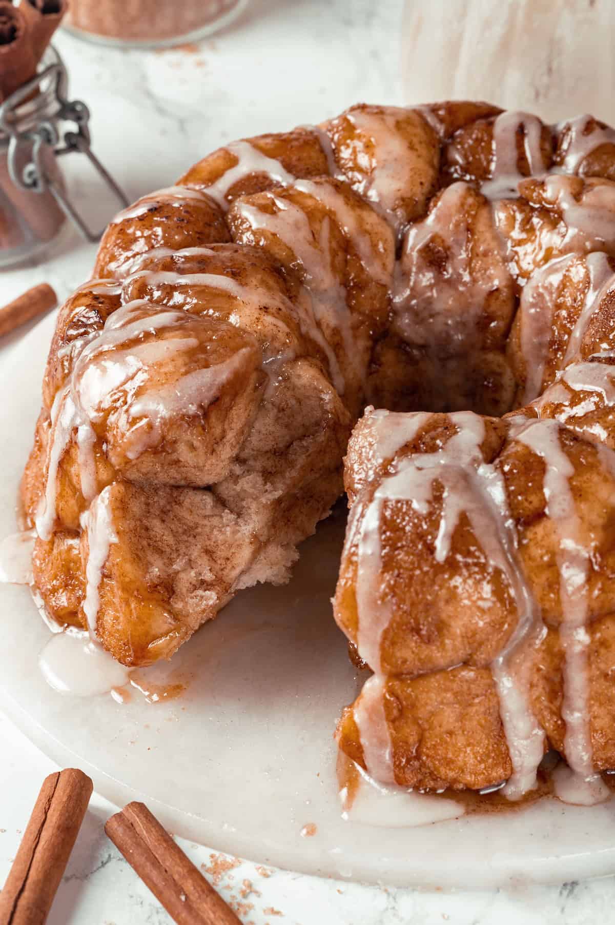 Soft, gooey and sticky, this Vegan Monkey Bread recipe is an irresistible pull-apart treat that's perfect for weekend brunches and holidays! Monkey bread on platter with pieces removed to show texture inside.