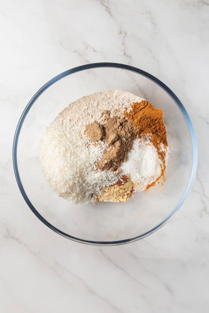 With cozy spices, carrots, pineapple, and apple, along with a nutty crunch, these vegan morning glory muffins are super moist and so delish! Dry ingredients for muffins in bowl before whisking.