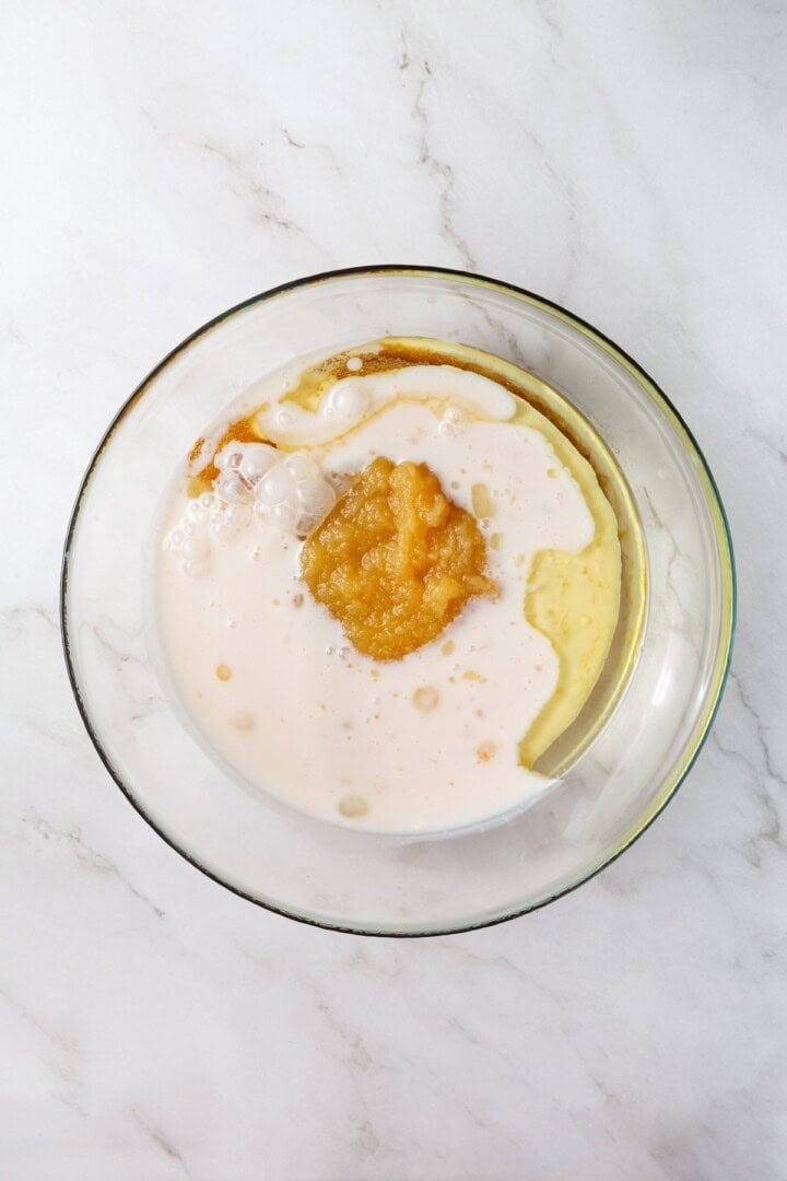 With cozy spices, carrots, pineapple, and apple, along with a nutty crunch, these vegan morning glory muffins are super moist and so delish! Wet ingredients for vegan muffins in glass bowl before mixing.