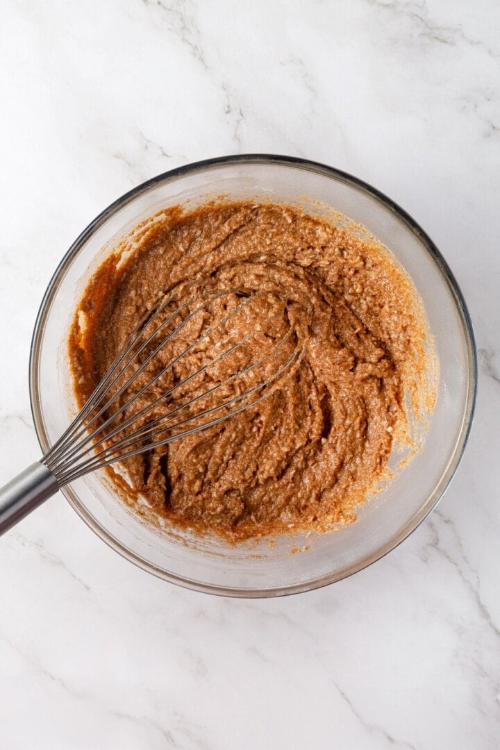 With cozy spices, carrots, pineapple, and apple, along with a nutty crunch, these vegan morning glory muffins are super moist and so delish! Whisking batter for morning glory muffins in bowl.