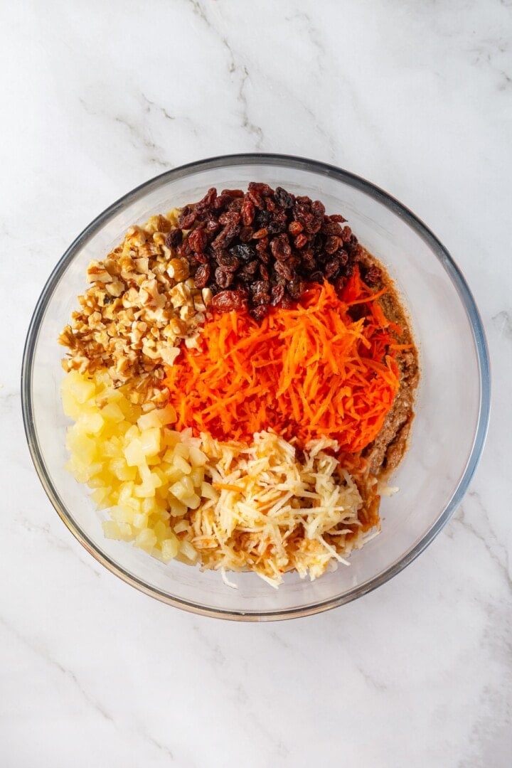 With cozy spices, carrots, pineapple, and apple, along with a nutty crunch, these vegan morning glory muffins are super moist and so delish! Ingredients for morning glory muffins in glass bowl.