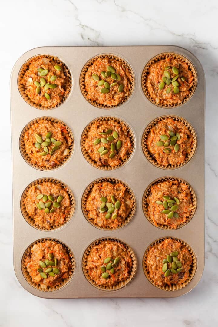 With cozy spices, carrots, pineapple, and apple, along with a nutty crunch, these vegan morning glory muffins are super moist and so delish! Overhead view of morning glory muffin batter in pan.