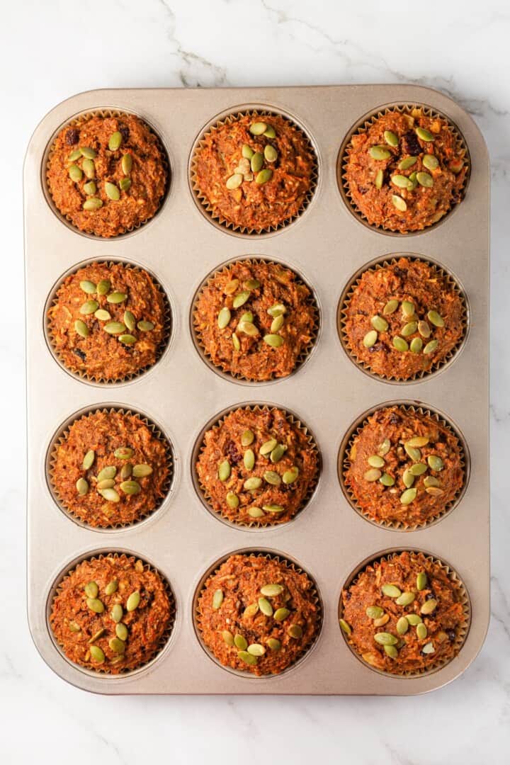 With cozy spices, carrots, pineapple, and apple, along with a nutty crunch, these vegan morning glory muffins are super moist and so delish! Overhead view of morning glory muffins in pan.