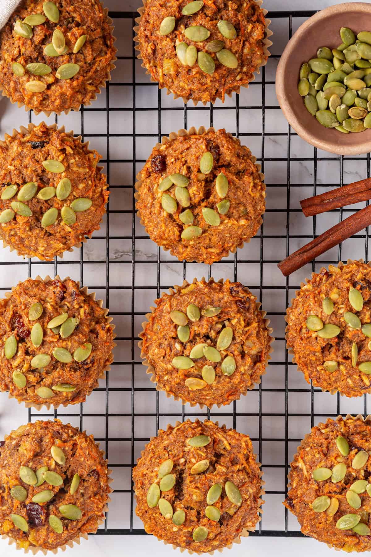 With cozy spices, carrots, pineapple, and apple, along with a nutty crunch, these vegan morning glory muffins are super moist and so delish! Overhead view of morning glory muffins on wire rack.